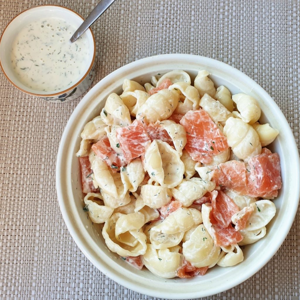 A bowl of smoked salmon pasta salad with a dish of homemade ranch dressing.