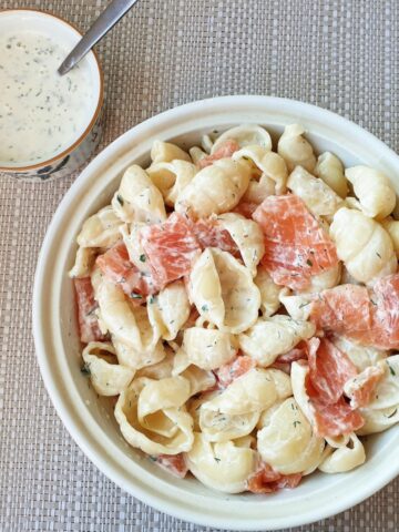 A bowl of smoked salmon pasta salad with a dish of homemade ranch dressing.