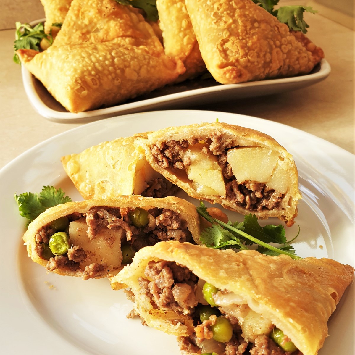 Two beef samosas cut open on a plate, showing the inside.