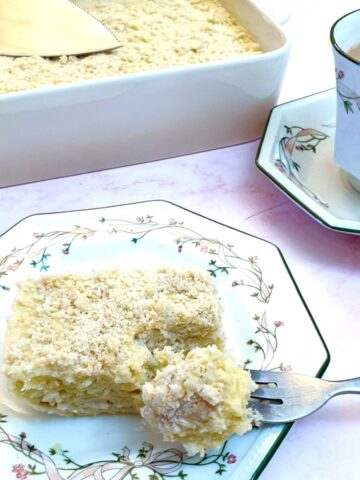 A slice of pineapple fridge tart on a plate next to a cup of tea.