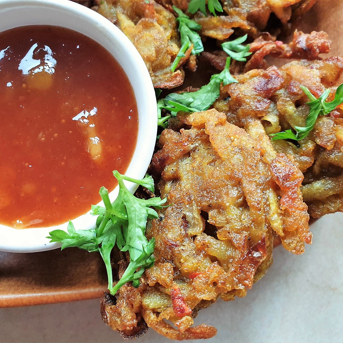 Close up of a potato and onion bhaji with dipping sauces.