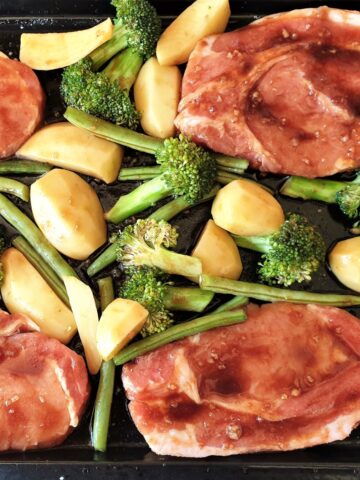 Pork chops on a baking sheet with vegetables.