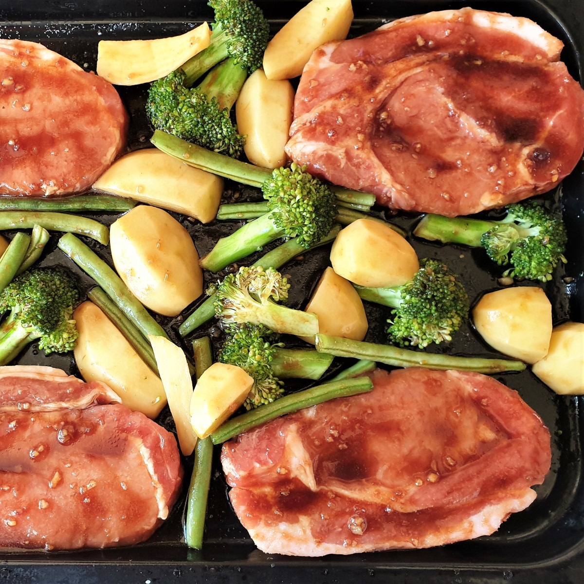Pork chops on a baking sheet with vegetables.