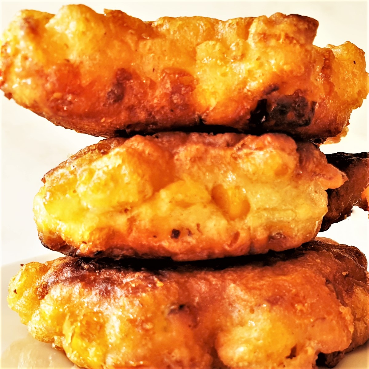 A pile of three fried crispy sweetcorn fritters.