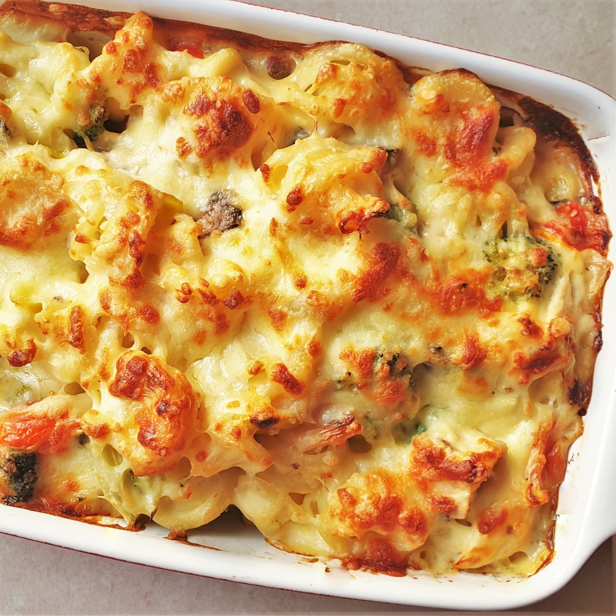 A baked dish of cheesy chicken and vegetable pasta.