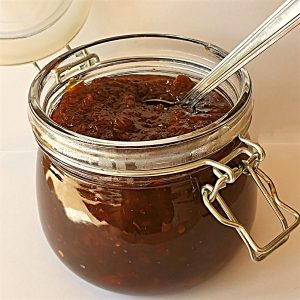 An open jar of Mrs Balls chutney with a spoon.