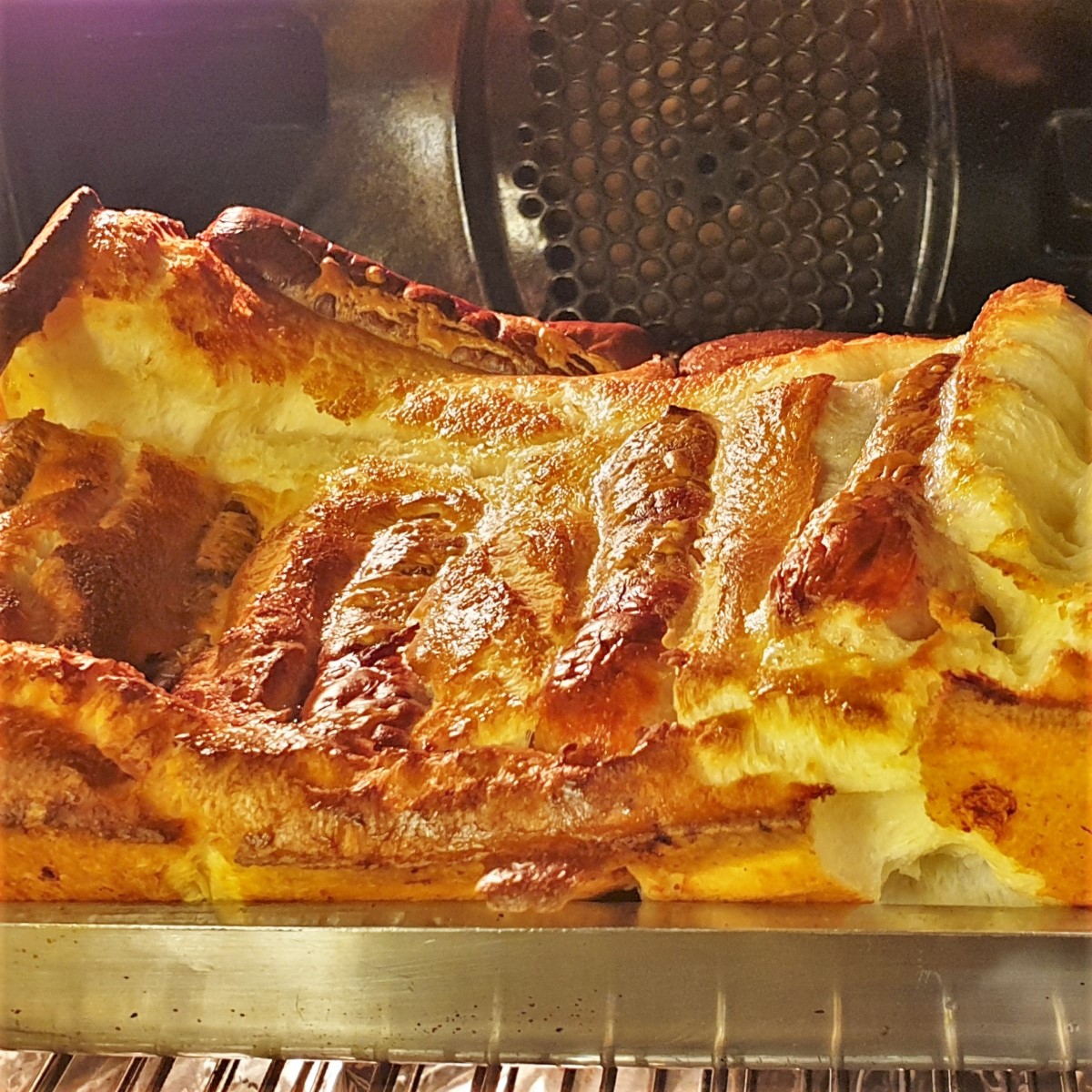 A tray of toad in the hole, showing the batter rising in the oven.