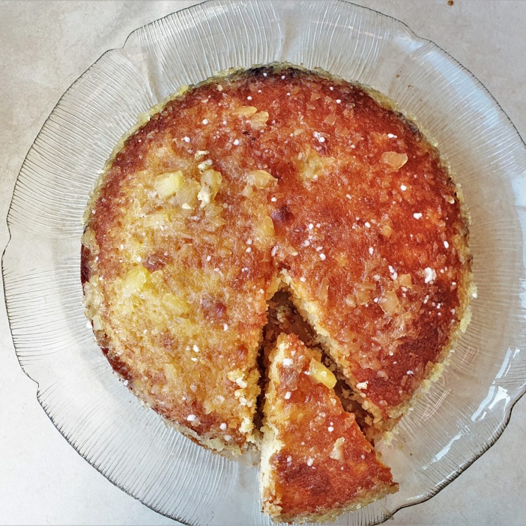 A pineapple coconut cake with a slice cut out.