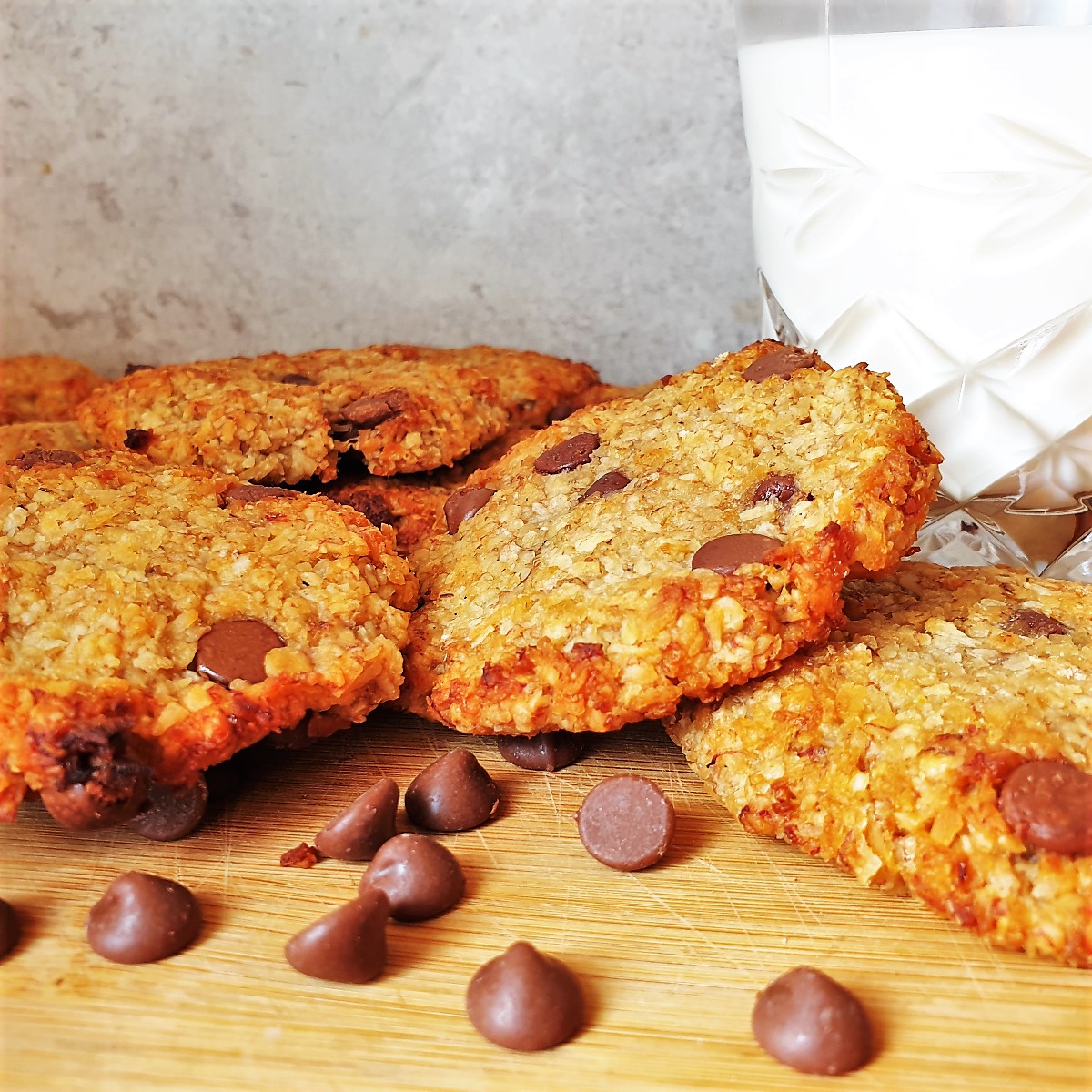 A pile of banana oat cakes in front of a glass of milk.