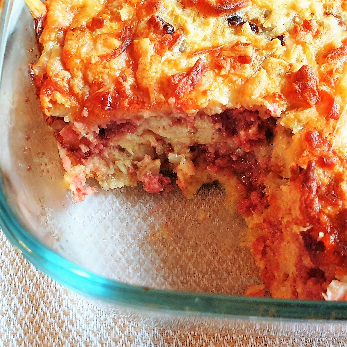 A bully beef quiche in a baking dish with a slice removed.