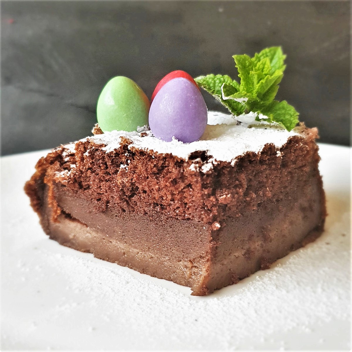 A slice of chocolate magic cake with 3 mini chocolate eggs on top.