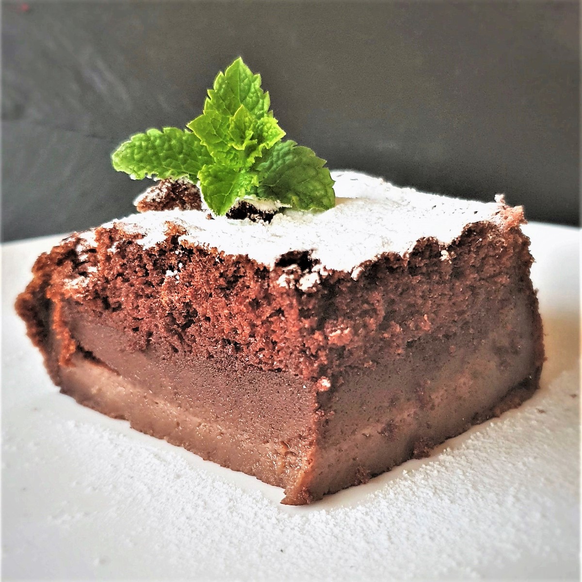 A slice of chocolate magic cake on a plate, clearly showing the three distinct layers.