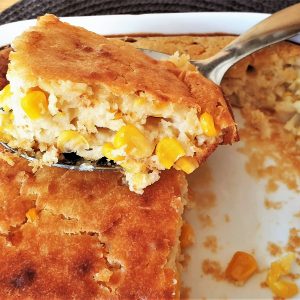 Baked cornbread in a baking dish with a spoonful being removed.