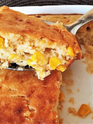 Baked cornbread in a baking dish with a spoonful being removed.