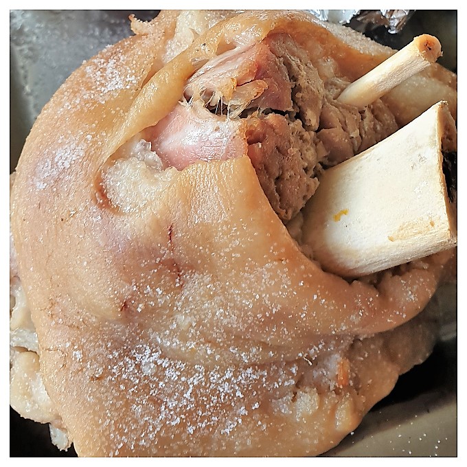 A cooked pork knuckle showing how the meat has retracted from the bone.