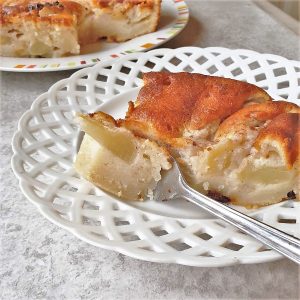 A slice of apple cake on a plate with a fork.