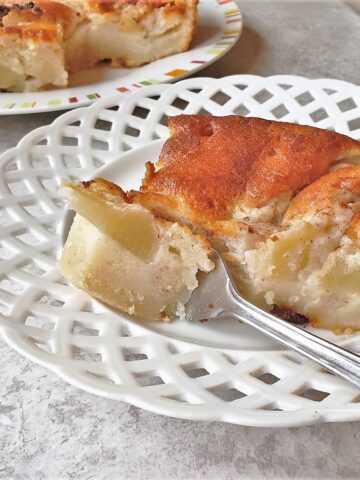 A slice of apple cake on a plate with a fork.