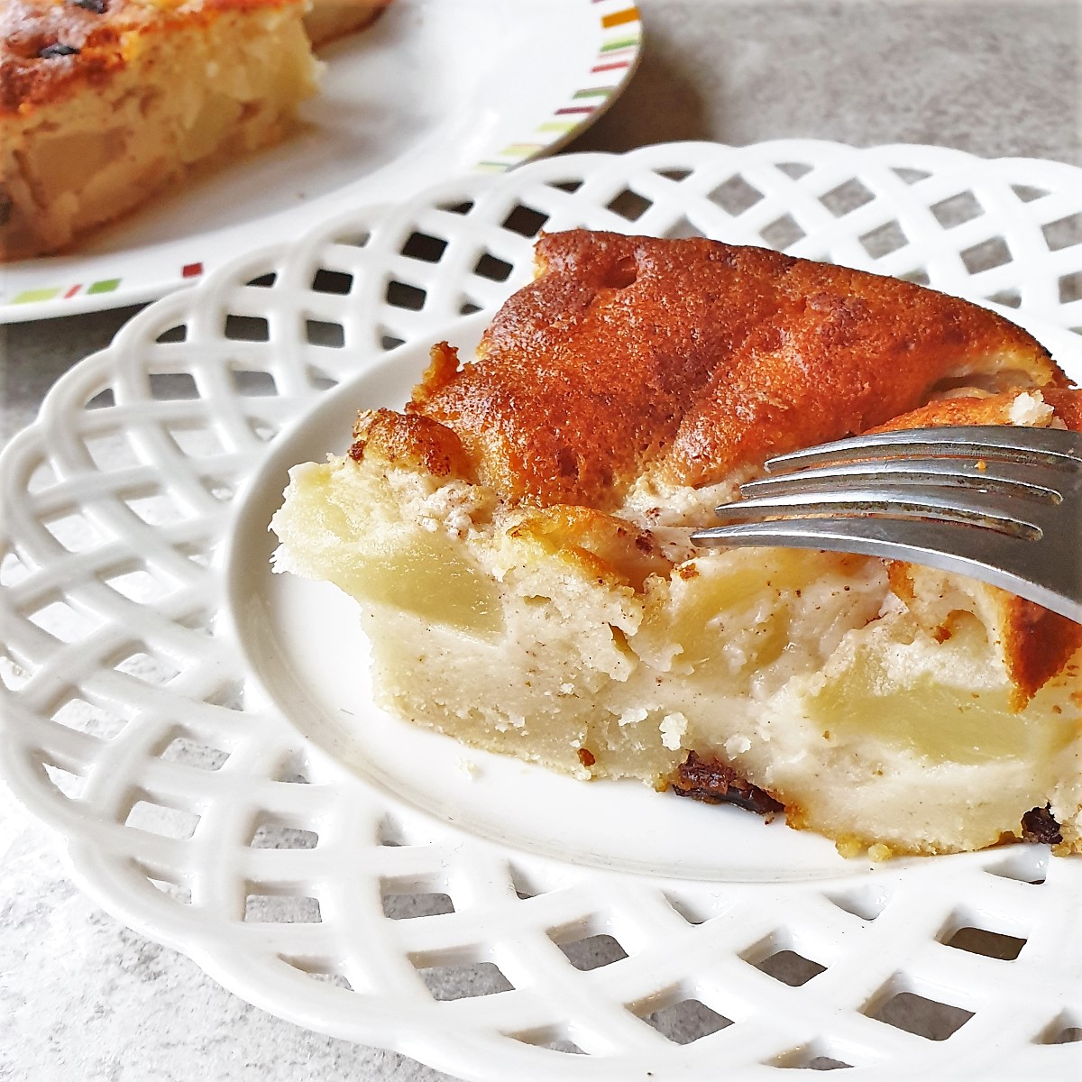 A slice of apple cake on a plate with a fork.