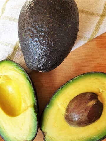 Two avocados - one whole one and the other cut in half.