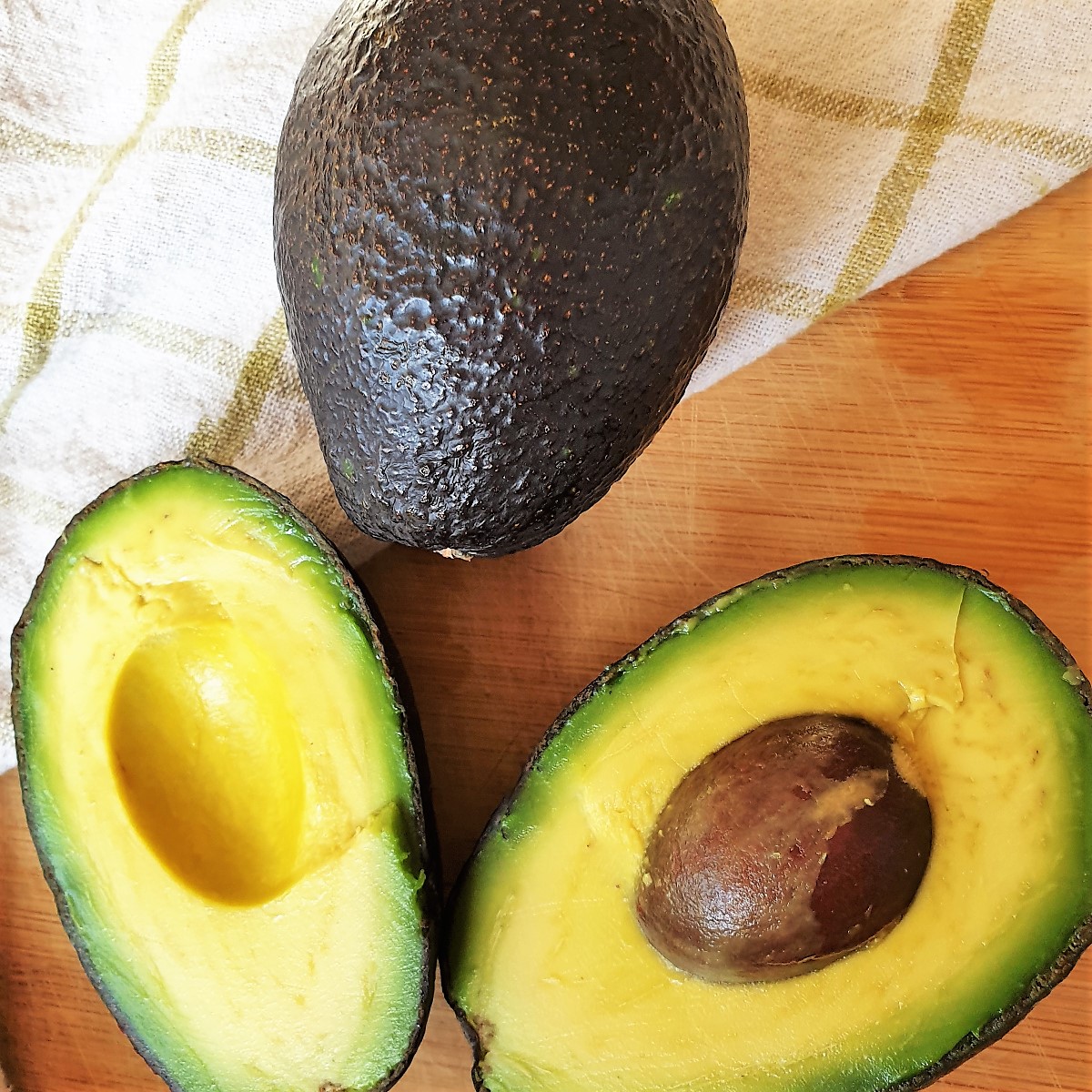 Two avocados - one whole one and one cut in half.