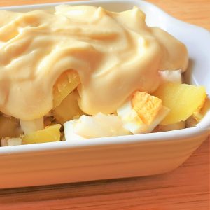 Potato salad in a dish, covered with homemade mayonnaise.