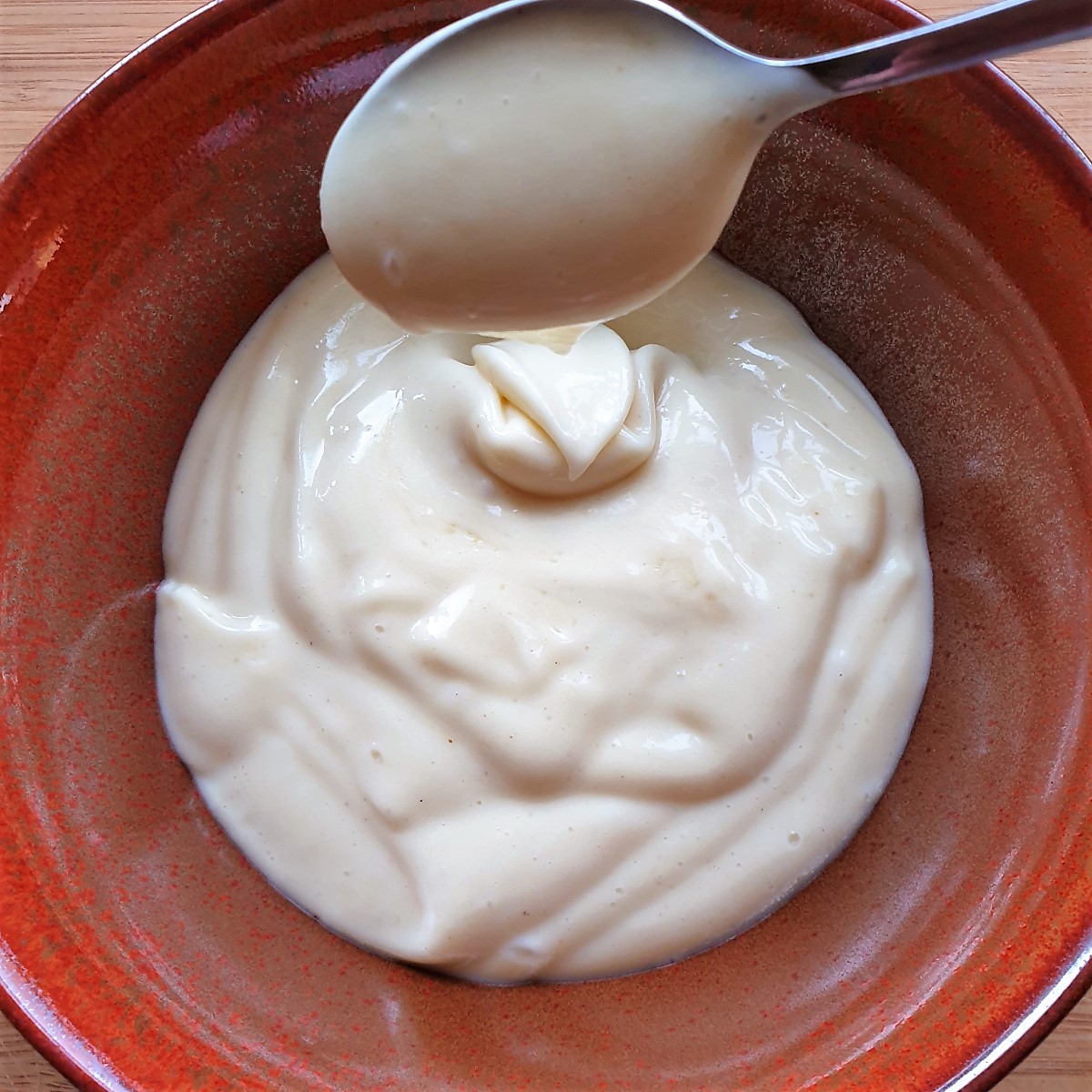 A bowl of homemade mayonnaise with a spoon.