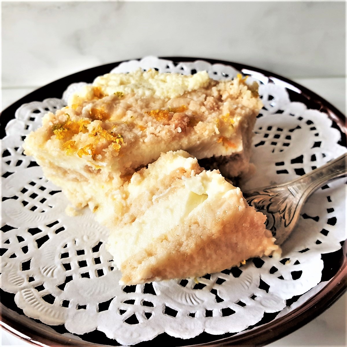 A slice of cictrus cheesecake on a doily on a plate with a fork.