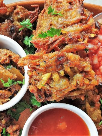 Close up of a potato and onion bhaji with dipping sauces.