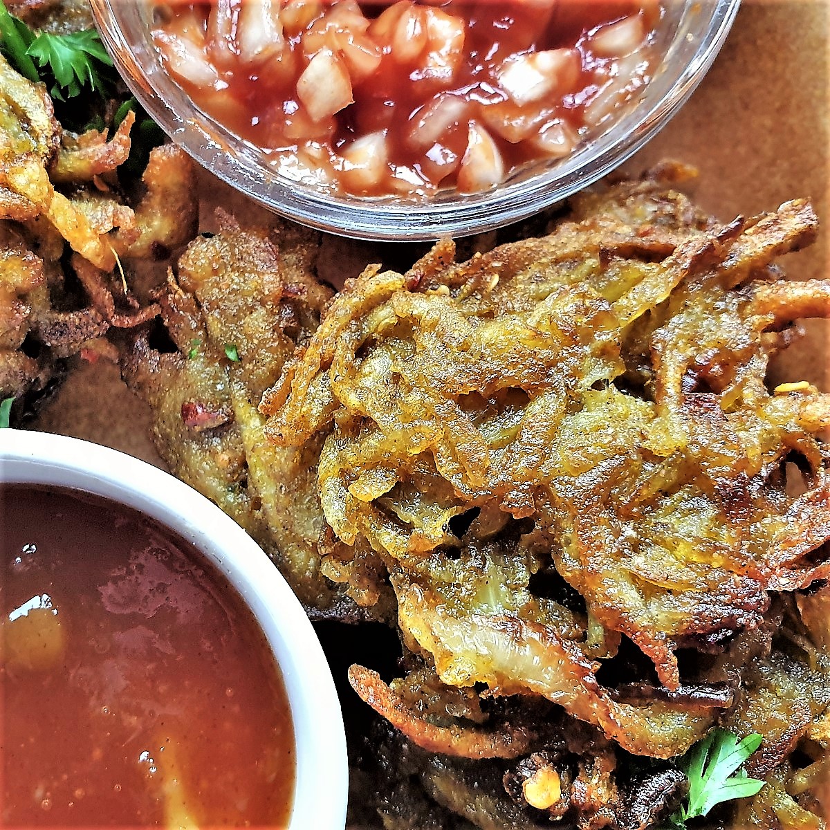 Close up of a potato and onion bhaji with dipping sauces.