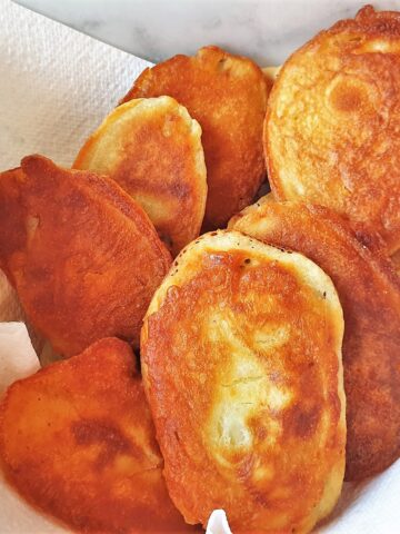 Fried scalloped potatoes in a bowl lined with kitchen paper.