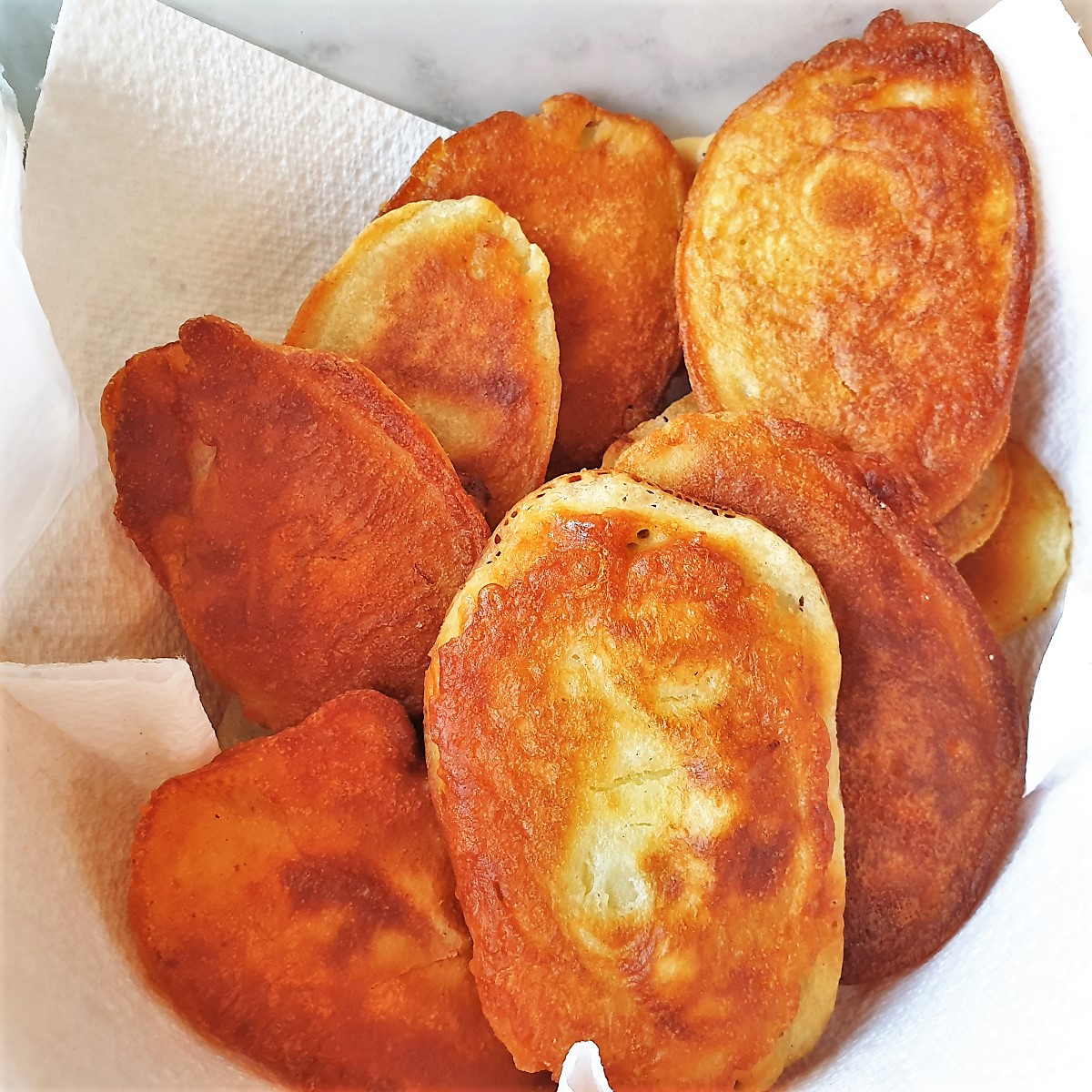 A dish of fried scalloped potatoes in batter.