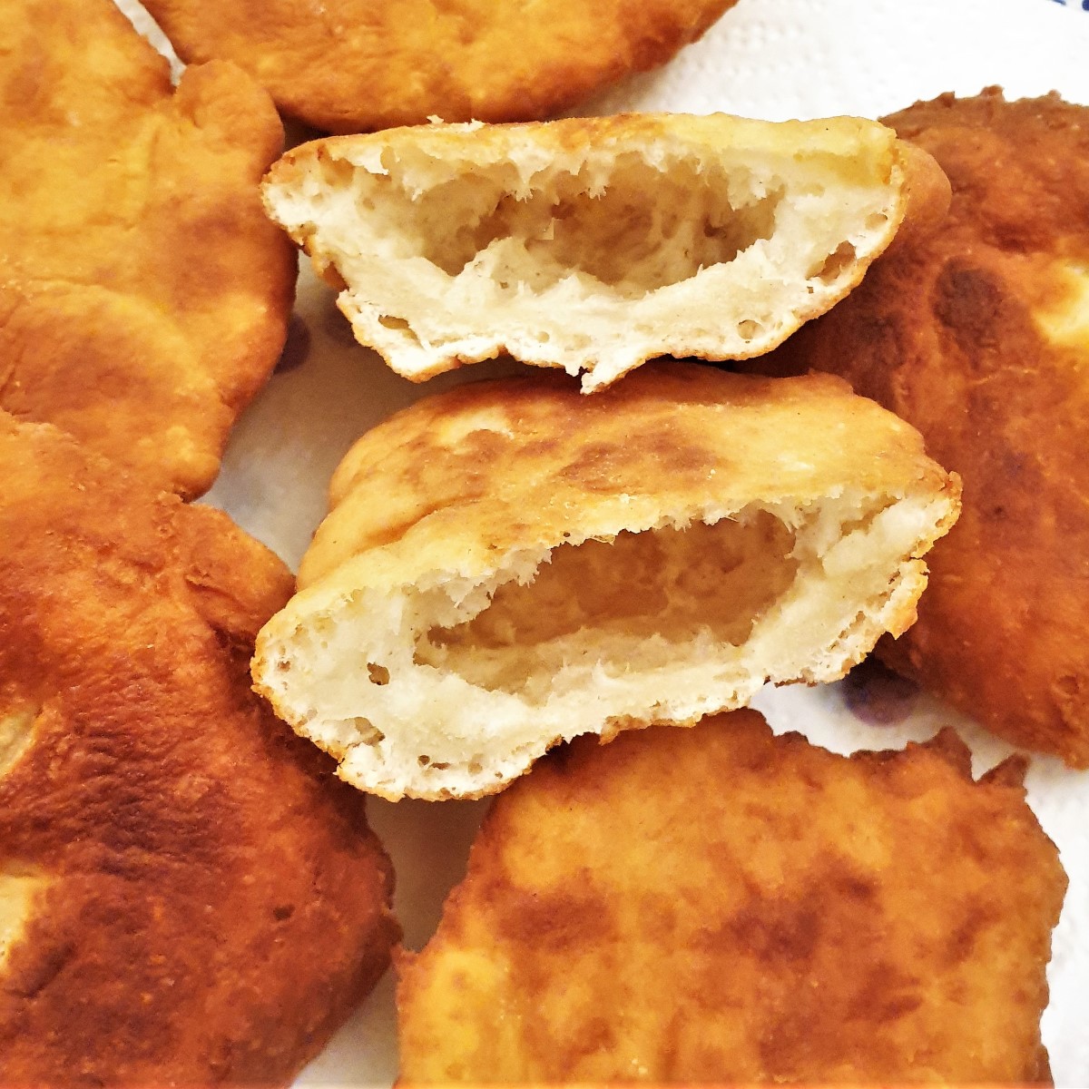 A pile of instant vetkoek with one cut open to show the inside.