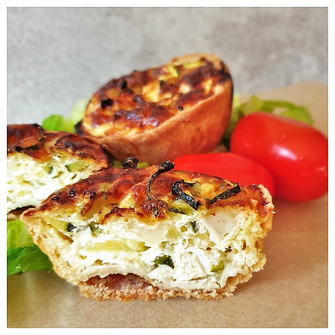 Zucchini and goat cheese tarts on a plate with tomatoes.