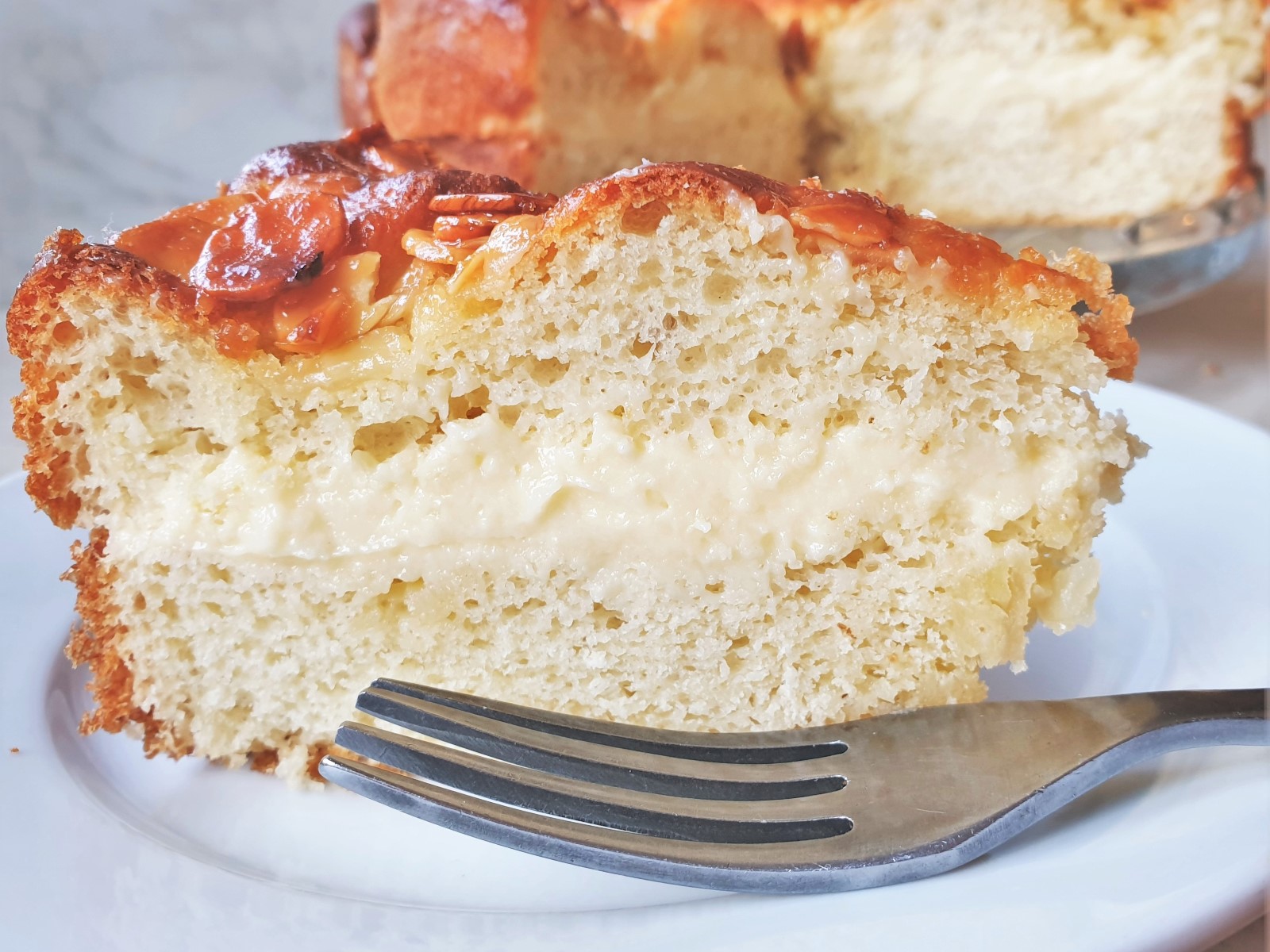 A slice of bee sting cake on a plate next to a fork. This shows the texture of the cake.