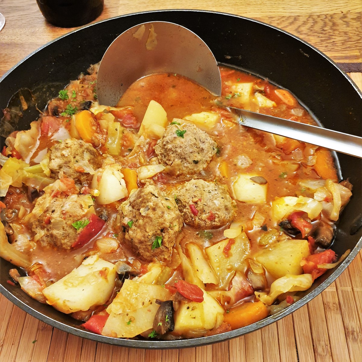 Meatball soup in a dish with a ladle.