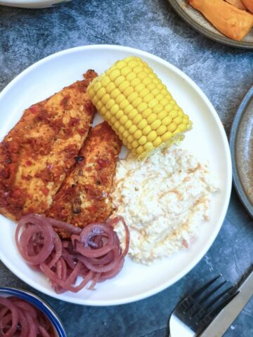 Overhead shot of 2 pieces of peri peri chicken on a plate with salads.