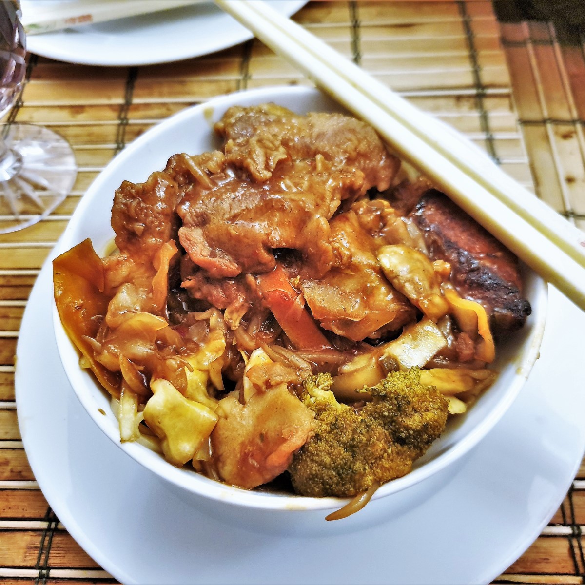A bowl of szechuan chicken with chopsticks.
