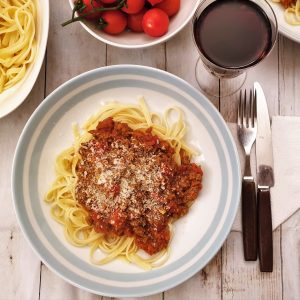 Overhead shot of a plate of bolognese spaghetti sauce sprinkled with parmesan cheese.