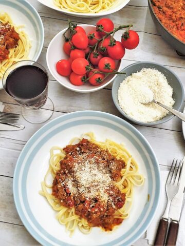 Overhead shot of a table set with plates of spaghetti bolognese.