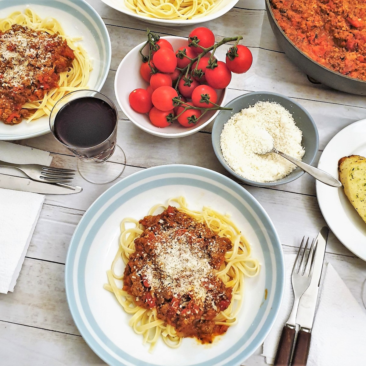 Overhead shot of a table set with plates of spaghetti bolognese.