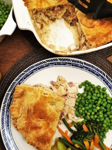 Chicken and ham pie on a plate with vegtables.