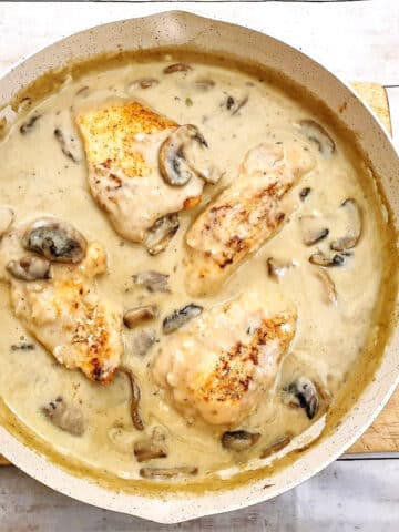 Overhead shot of chicken marsala swimming in creamy mushroom sauce in a frying pan.