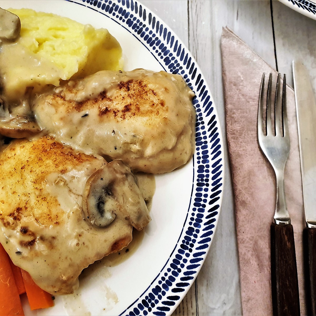 Two pieces of chicken marsala on a plate with vegetables.