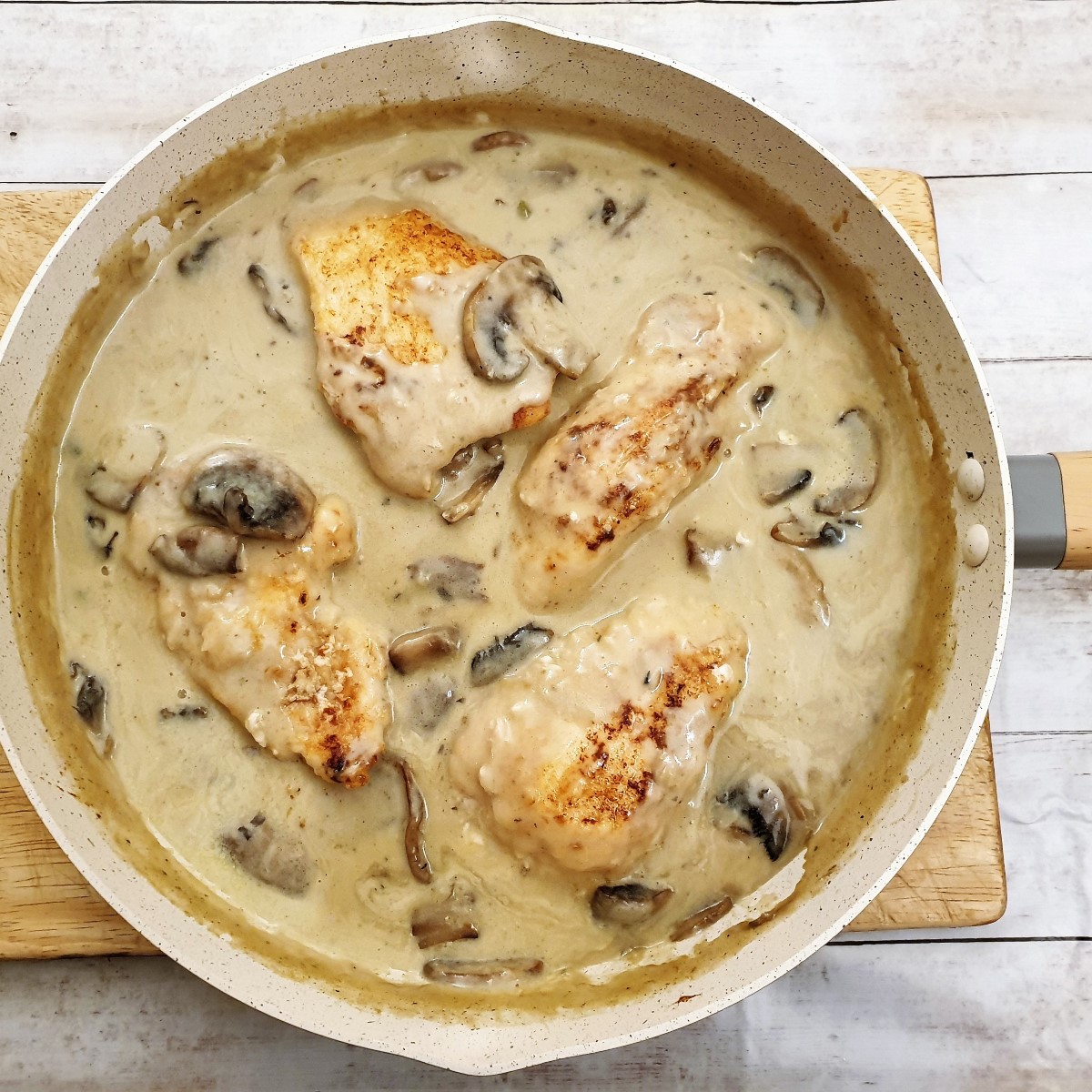 Chicken fillets cooking in marsala sauce in a frying pan.