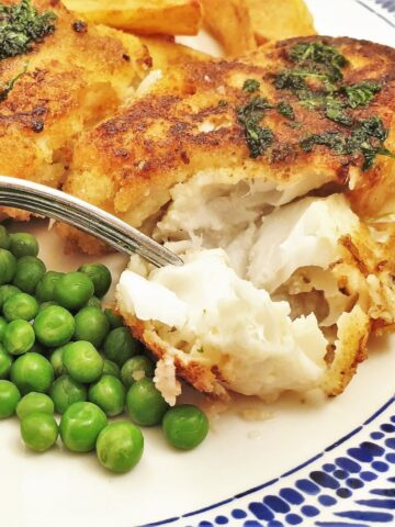 A piece of fish milanese being flaked with a fork.