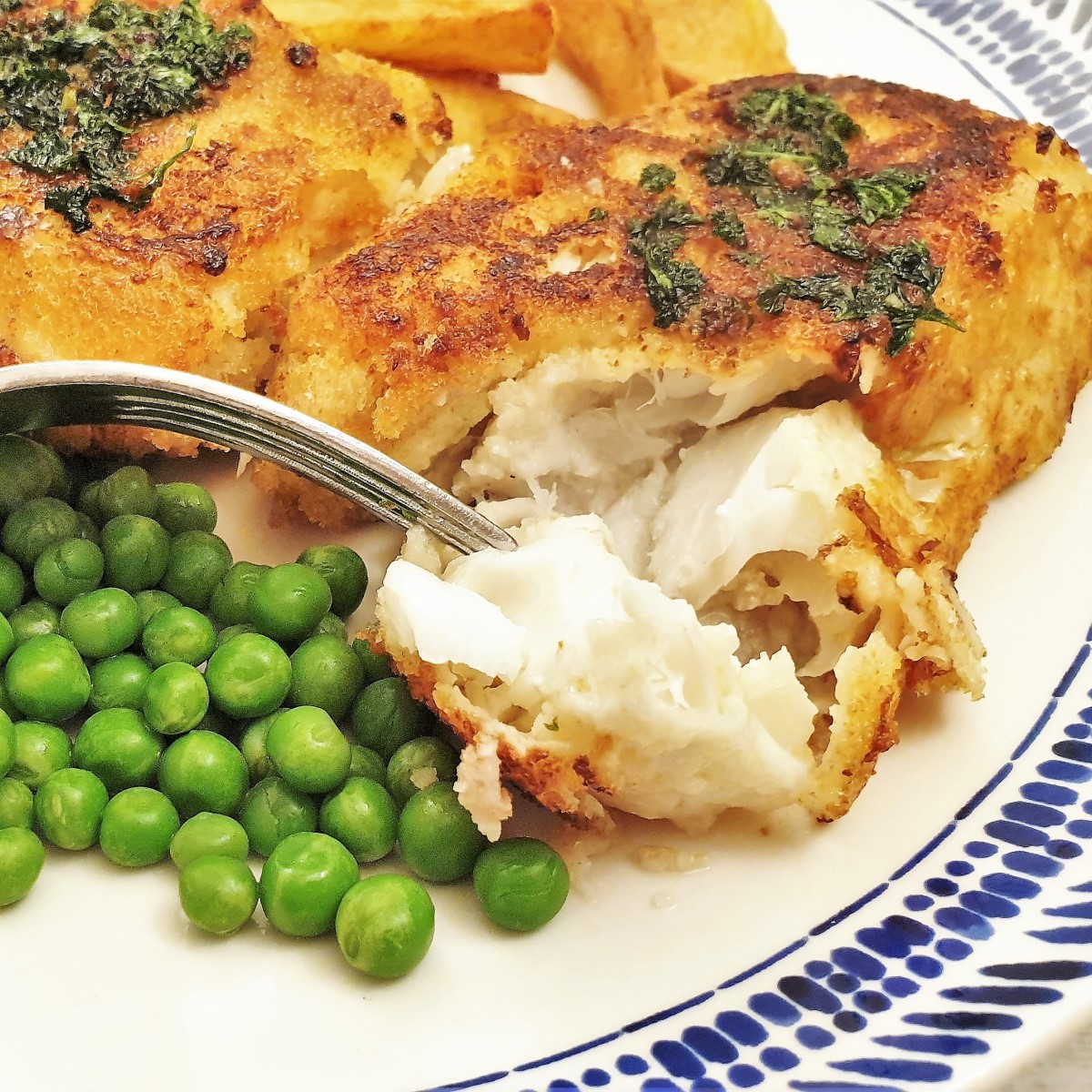 A piece of fish milanese being flaked with a fork.