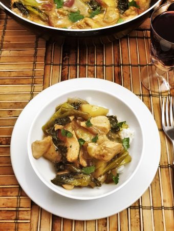 A table set with a bowl of thai green curry next to a dish of jasmine rice.