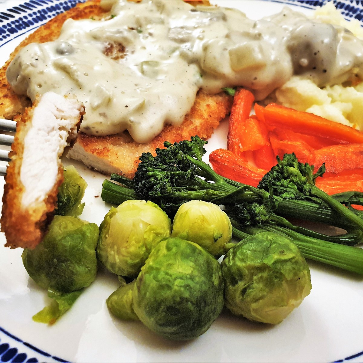 Close up of a chicken schnitzel with a piece of schnitzel on a fork.
