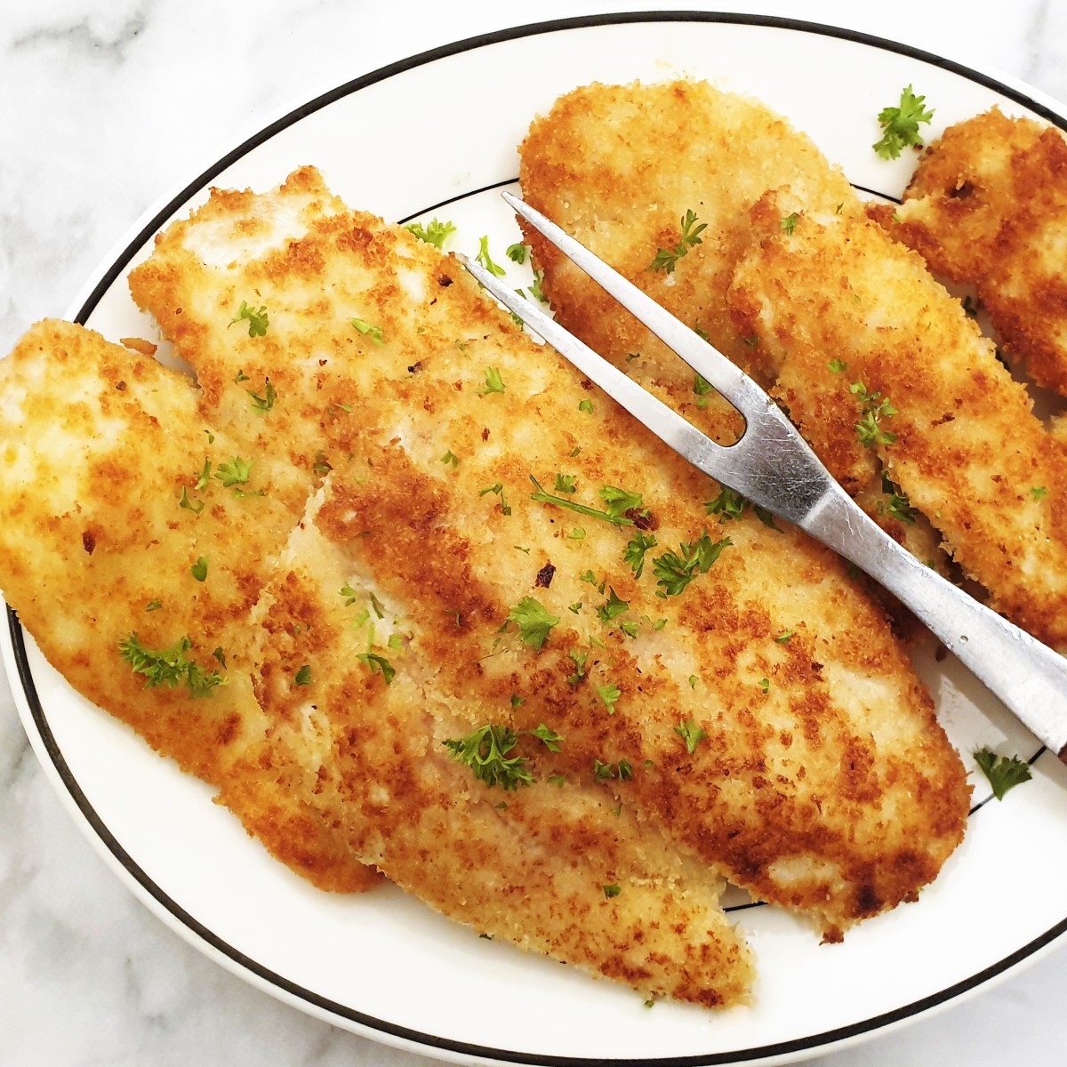 Fried chicken schnitzels on a plate. with a serving fork.
