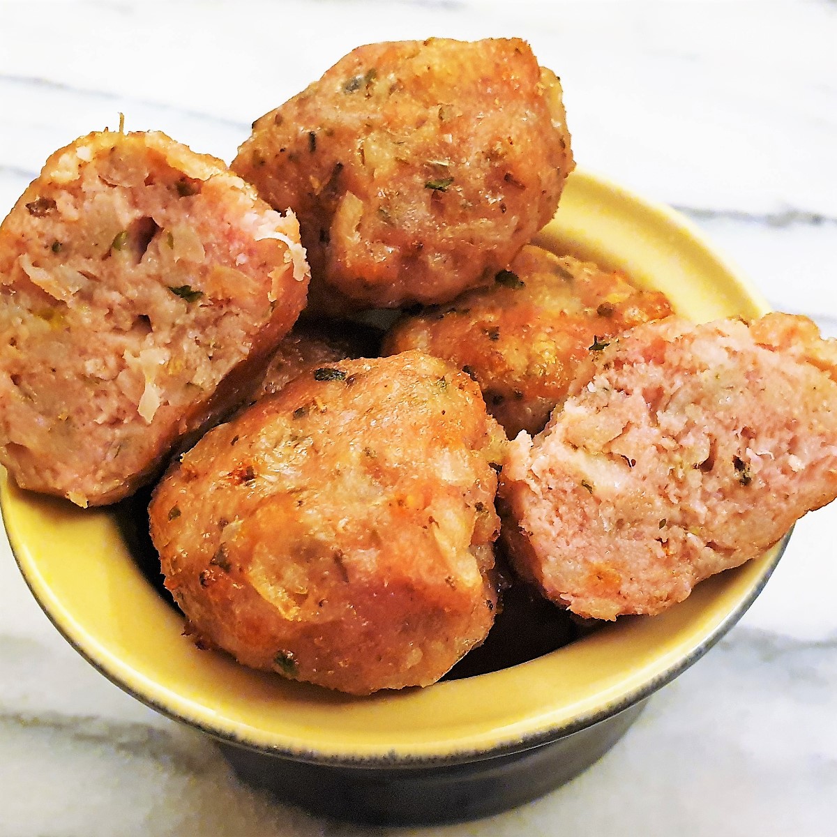 A bowl of sausage meat stuffing balls with one cut in half. A bowl of sausage meat stuffing balls with one cut in half.
